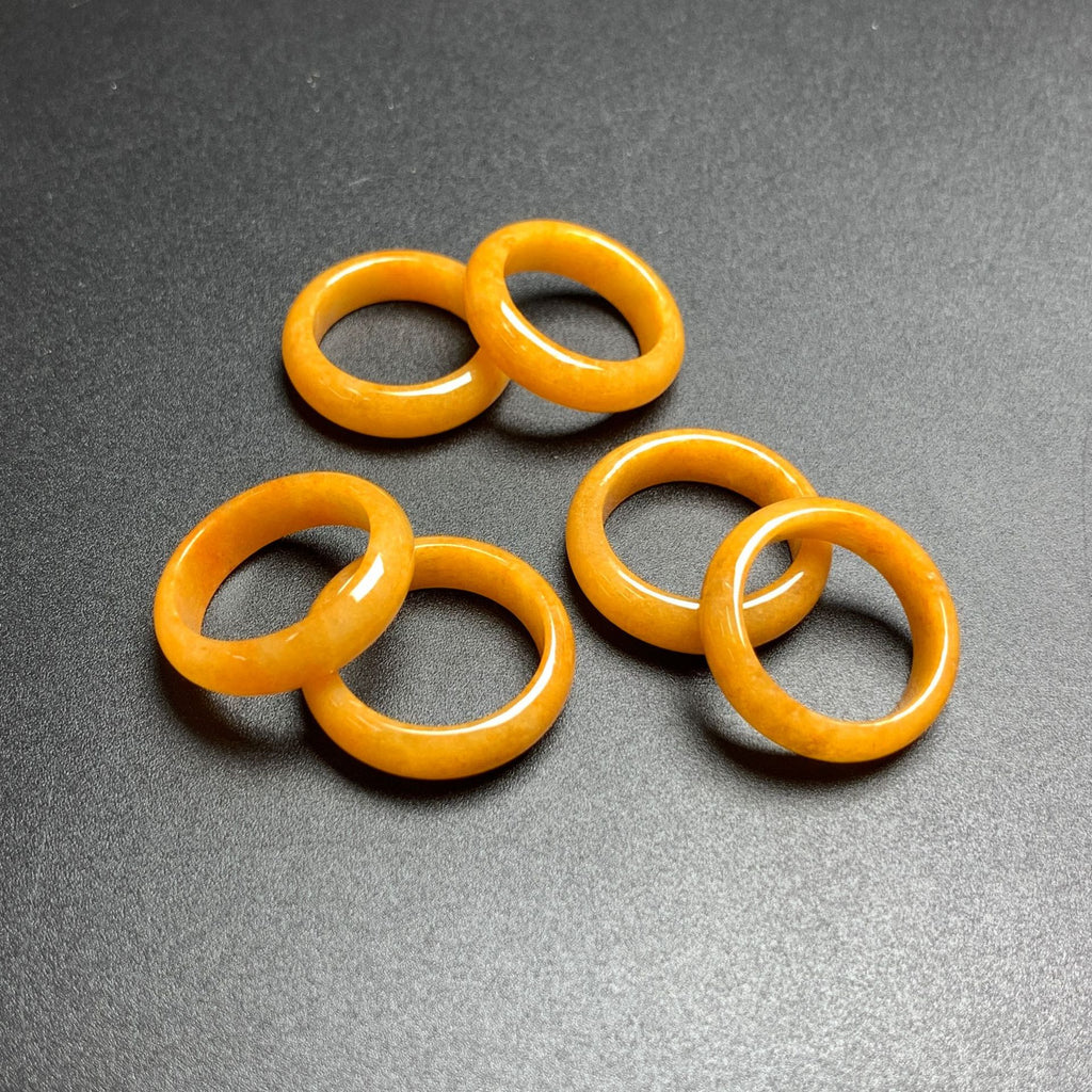 Golden yellow jadeite rings arranged on dark background with polished finish