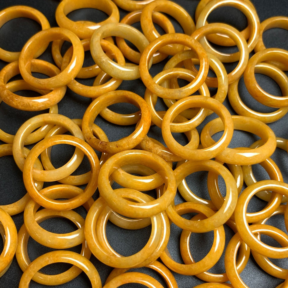 Collection of honey yellow jadeite band rings showing natural tone variation