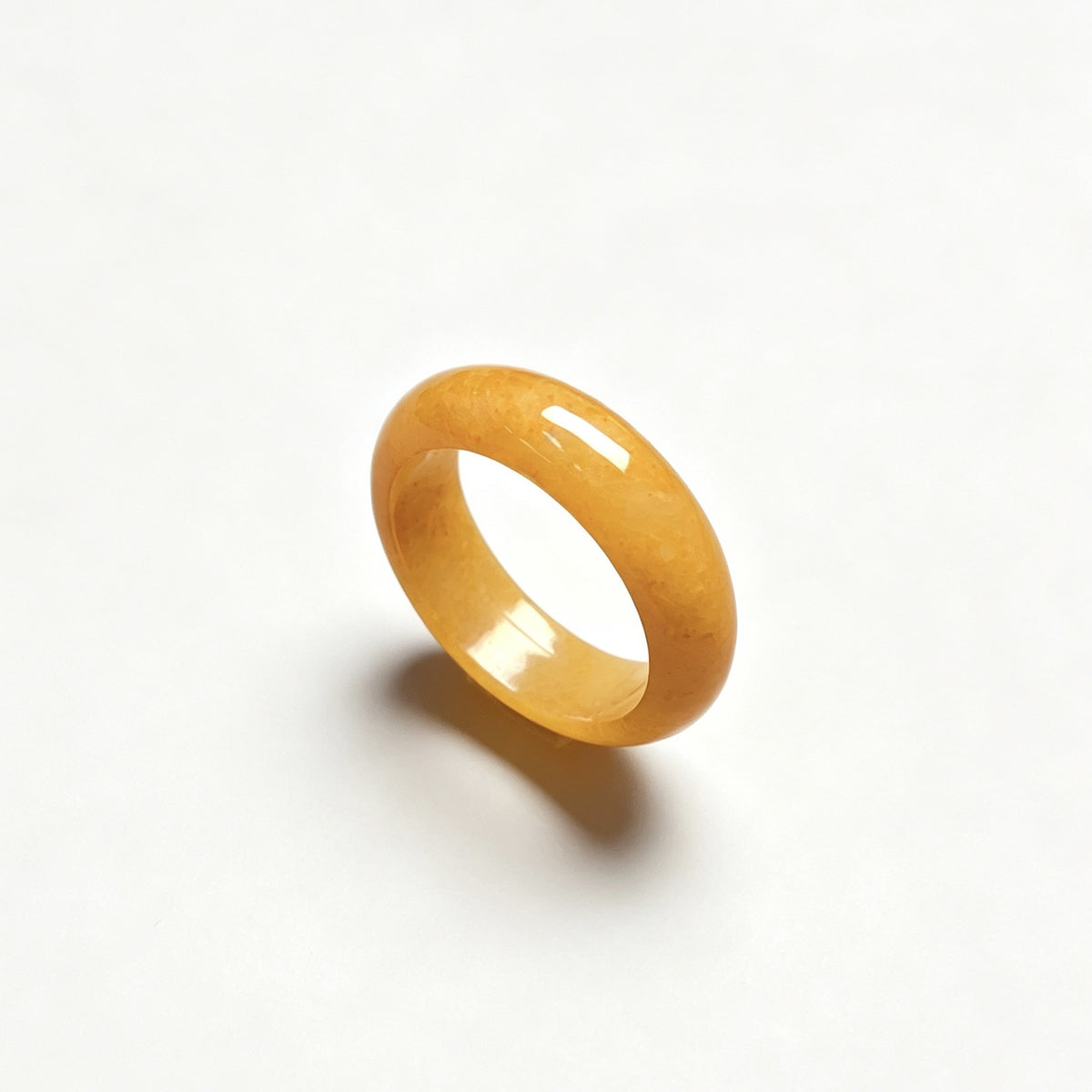 Polished golden yellow jadeite ring on white background