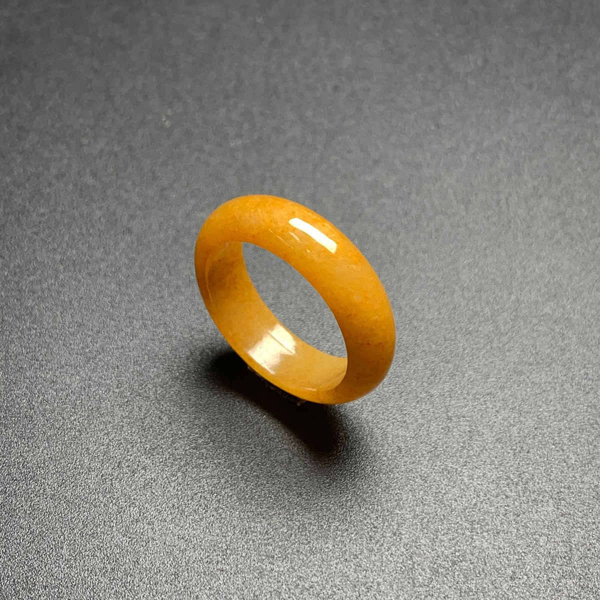 Honey yellow jadeite ring on dark background highlighting smooth stone luster