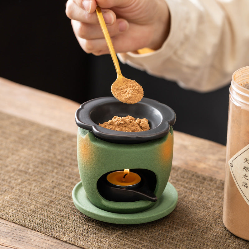 Adding aromatic powder to ceramic incense warmer above tea light candle