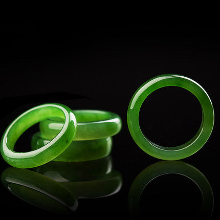 Natural green nephrite jade ring trio on black reflective surface