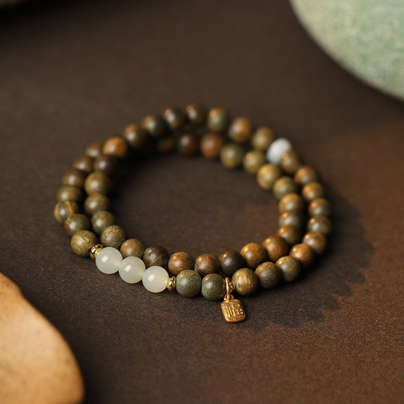 Green sandalwood-style double-wrap bracelet with pale jade-tone accent beads and small Fu plaque charm