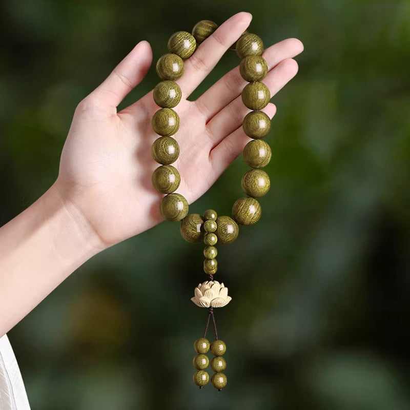 Green sandalwood-style 18mm hand strand with carved lotus accent shown against a deep green background