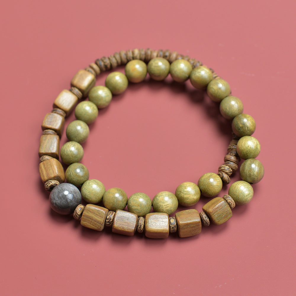 Green sandalwood-style double-layer wood bead bracelet arranged on red background with cube, round and disc bead textures