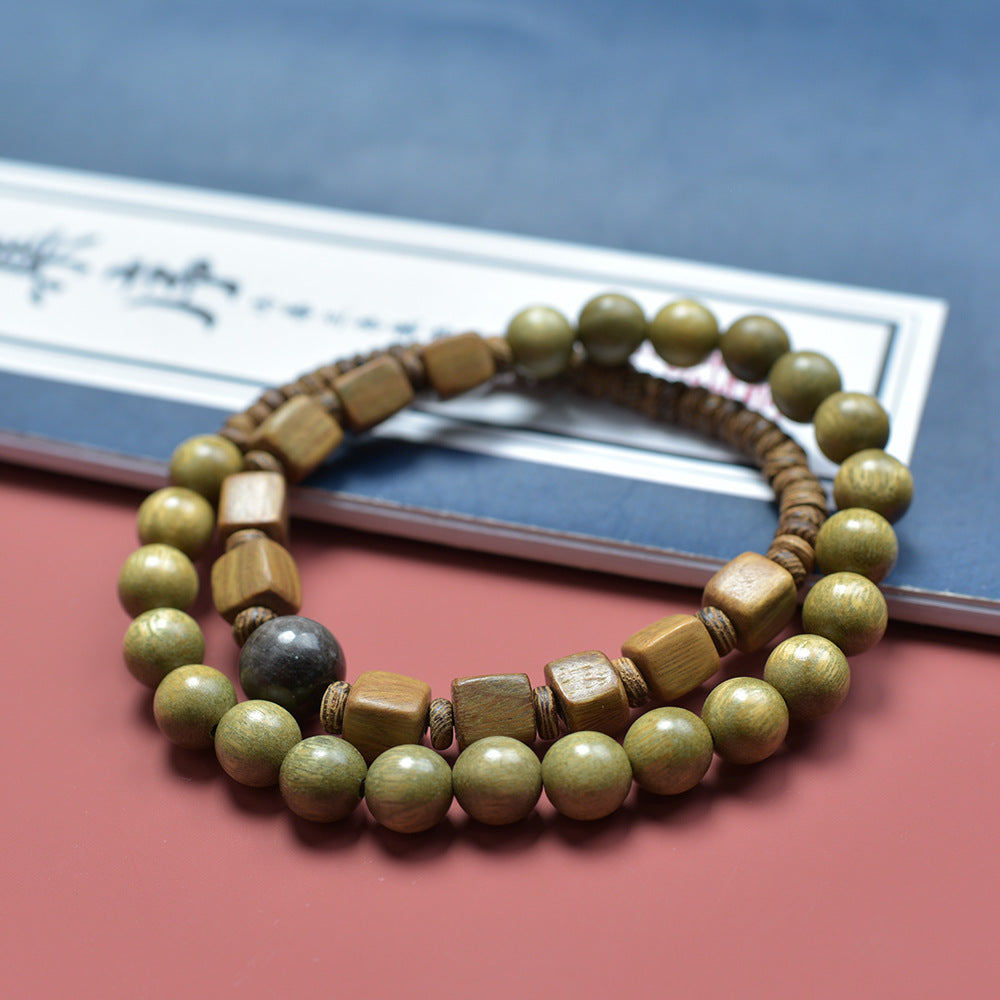 Green sandalwood-style double-layer wood bead bracelet styled beside a book for scholar desk and tea room display