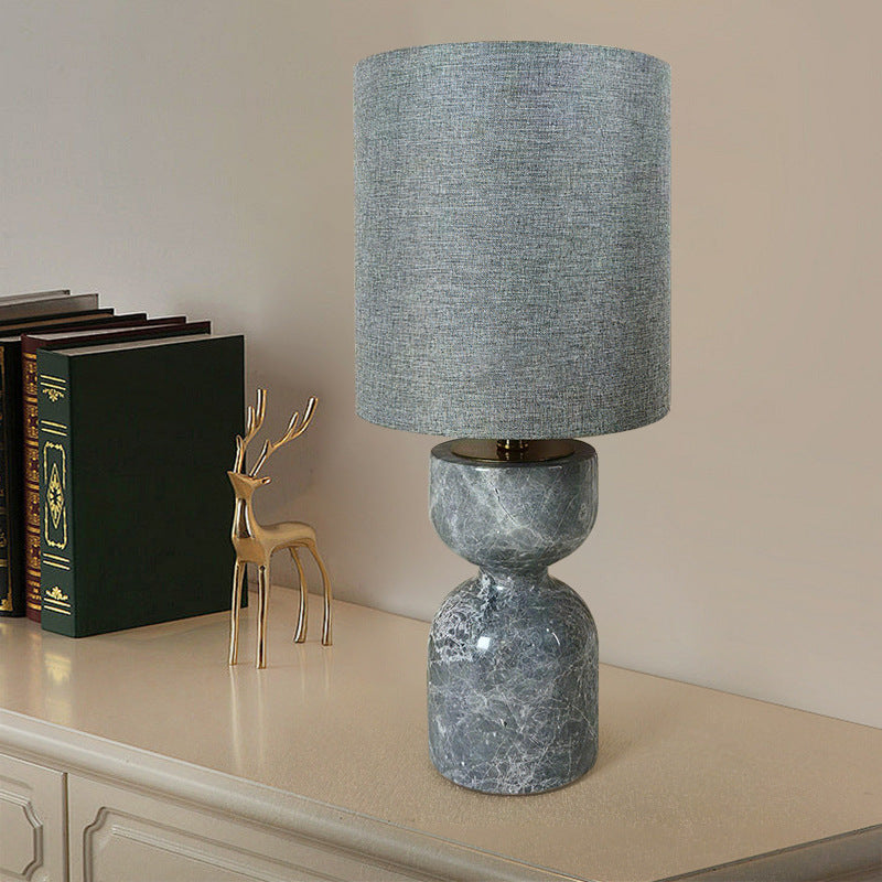 Grey marble hourglass table lamp with grey fabric cylinder shade on console