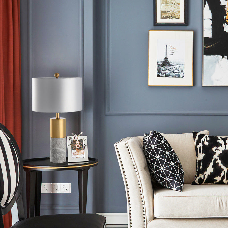 Grey marble brass table lamp styled beside chair in dark modern room