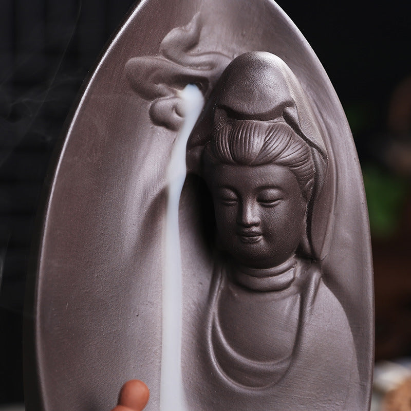 Close-up sculpted Guanyin face on leaf-shaped purple clay incense burner