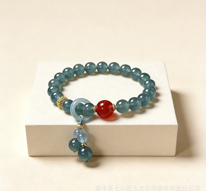 Blue water jadeite bead bracelet with red agate focal bead and gold tone spacers