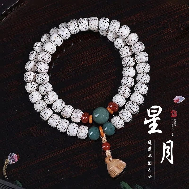 Natural white Hainan Xingyue Star Moon Bodhi prayer beads with multicolor accents and pale carved charm on dark background