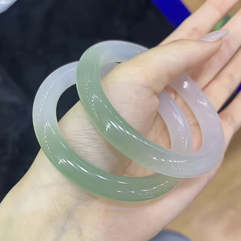 Two-tone green and pale lavender chalcedony bangles held in hand