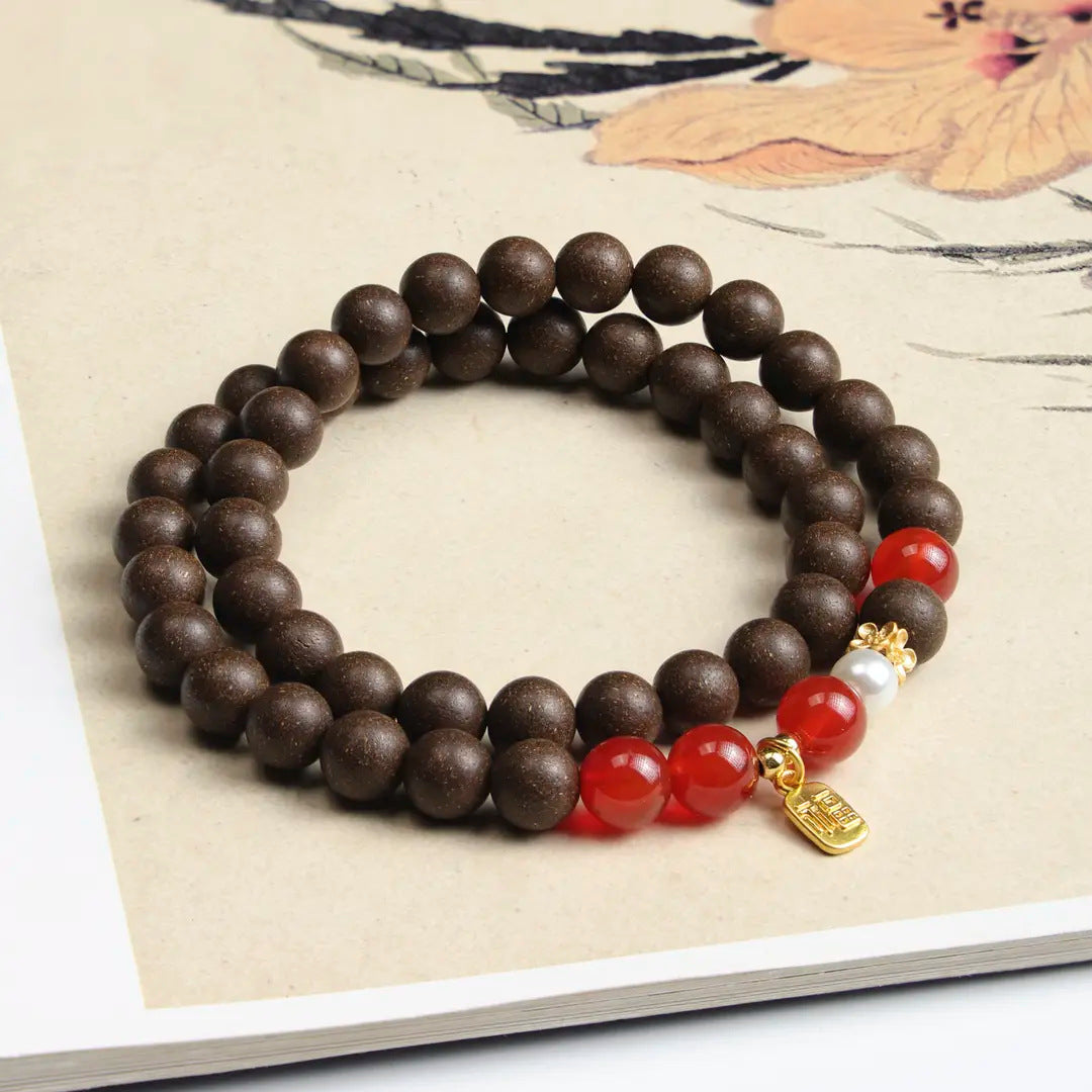 Dark brown herbal incense bead double-wrap bracelet with red accent beads, pearl-tone focal bead and gold-tone charm