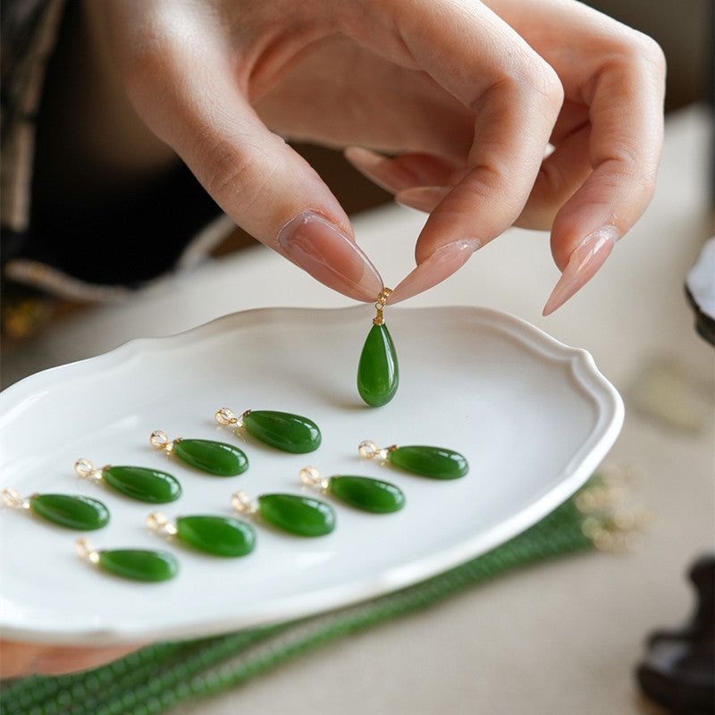 Natural spinach green nephrite teardrop pendant polished surface close up