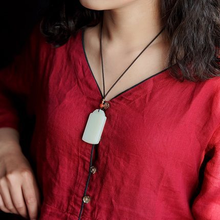 Natural Hetian jade Wu Shi Pai necklace worn with red linen top