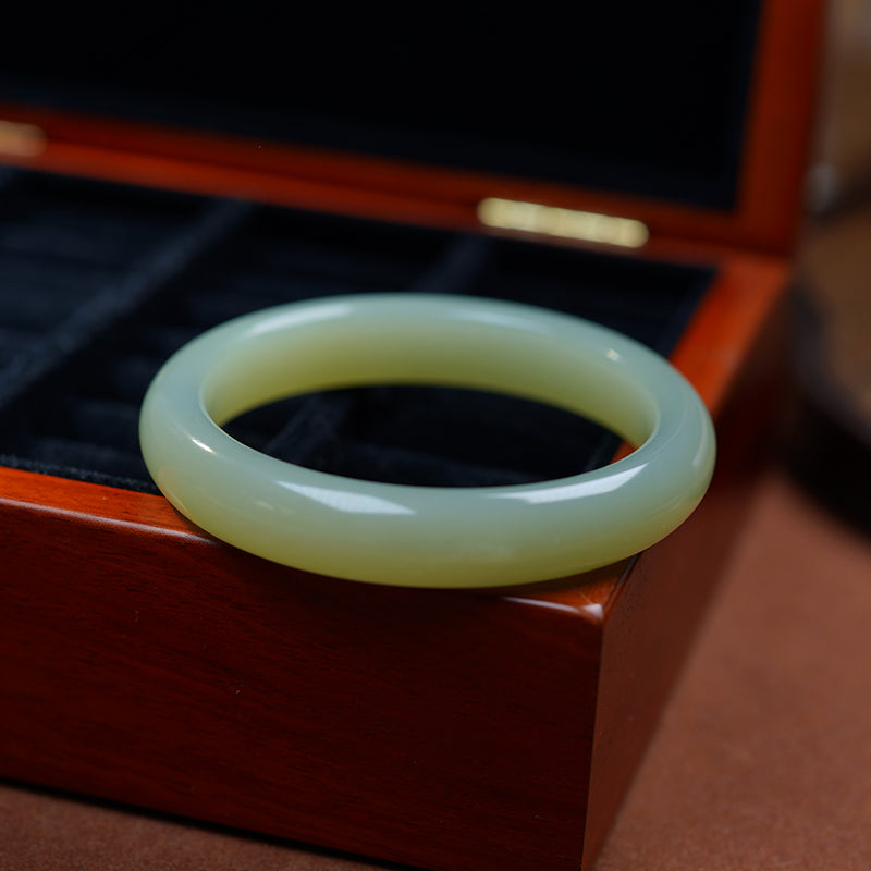 Hetian nephrite Qing Shui bangle polished on dark wood display