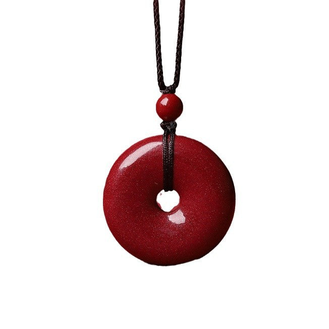 Red cinnabar donut pendant on black woven necklace cord