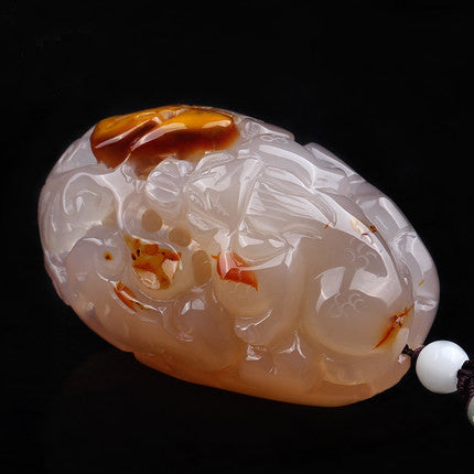 Large carved chalcedony Pixiu palm stone showing honey orange color zones
