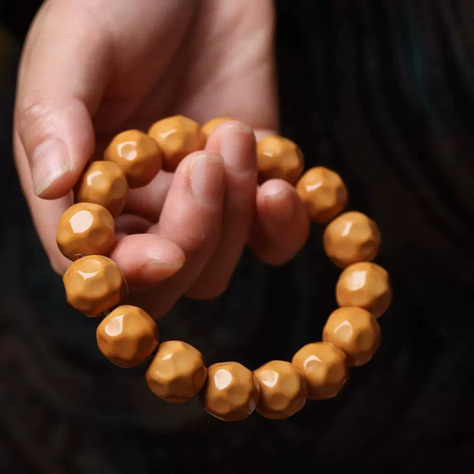 Warm caramel Houtou Wuxiang Bodhi bracelet held in hand showing polished irregular cheese-style bead shape