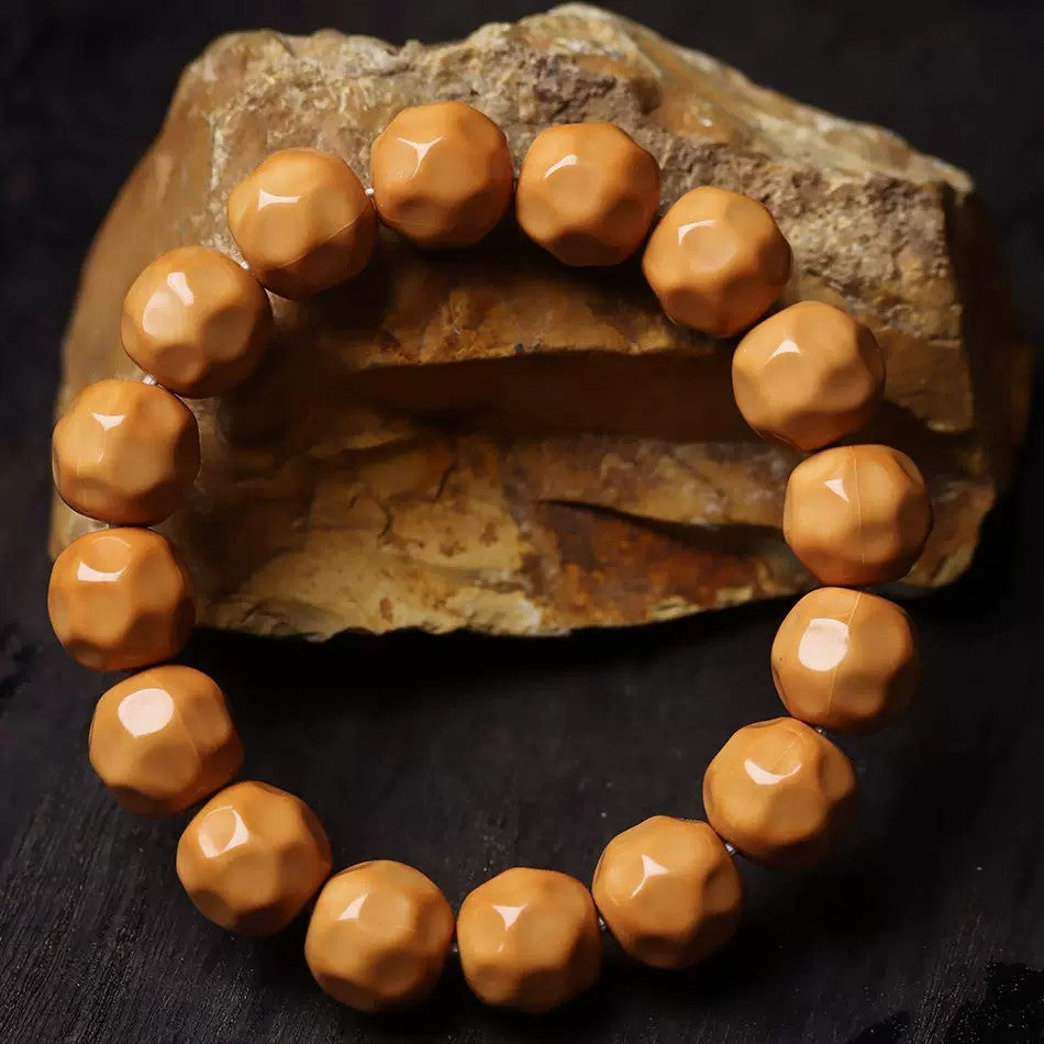 Houtou Wuxiang Bodhi bracelet with glossy caramel faceted beads displayed against a natural rock background