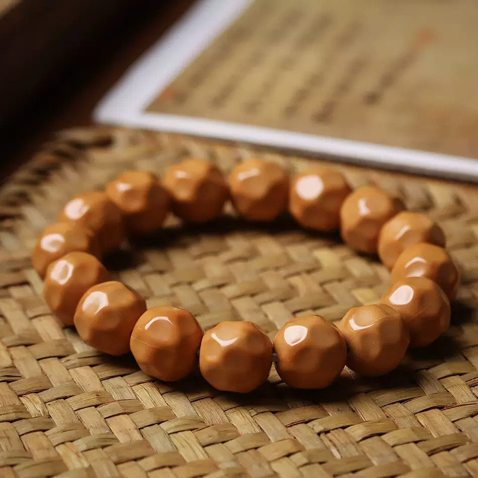 Houtou Wuxiang Bodhi bracelet displayed on woven bamboo mat beside a book for tea room and scholar study styling