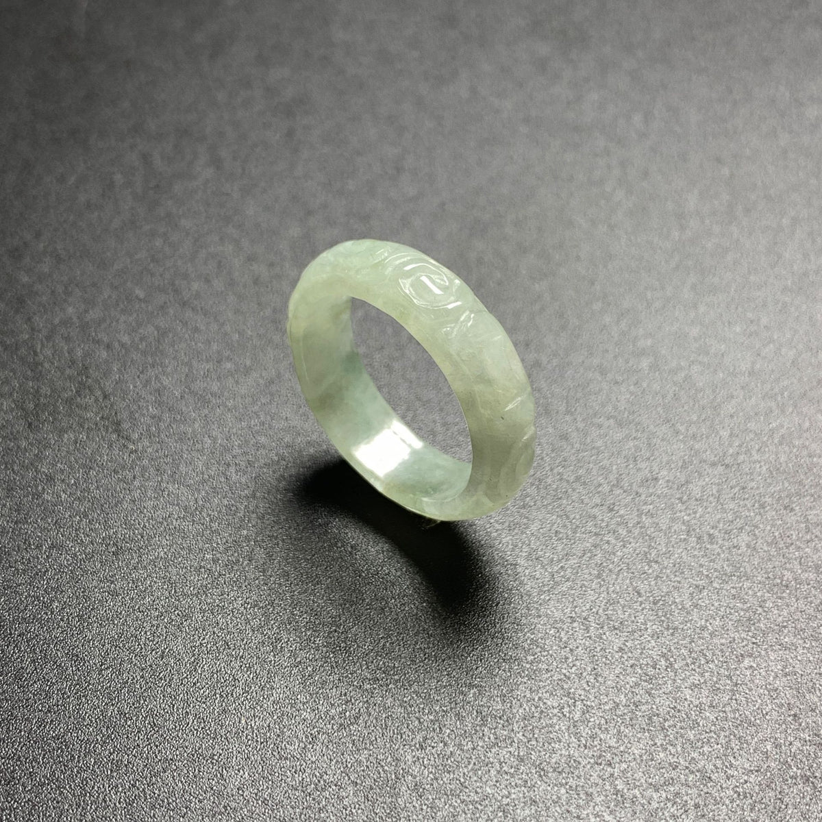 Pale green carved jadeite ring showing translucent icy glutinous texture