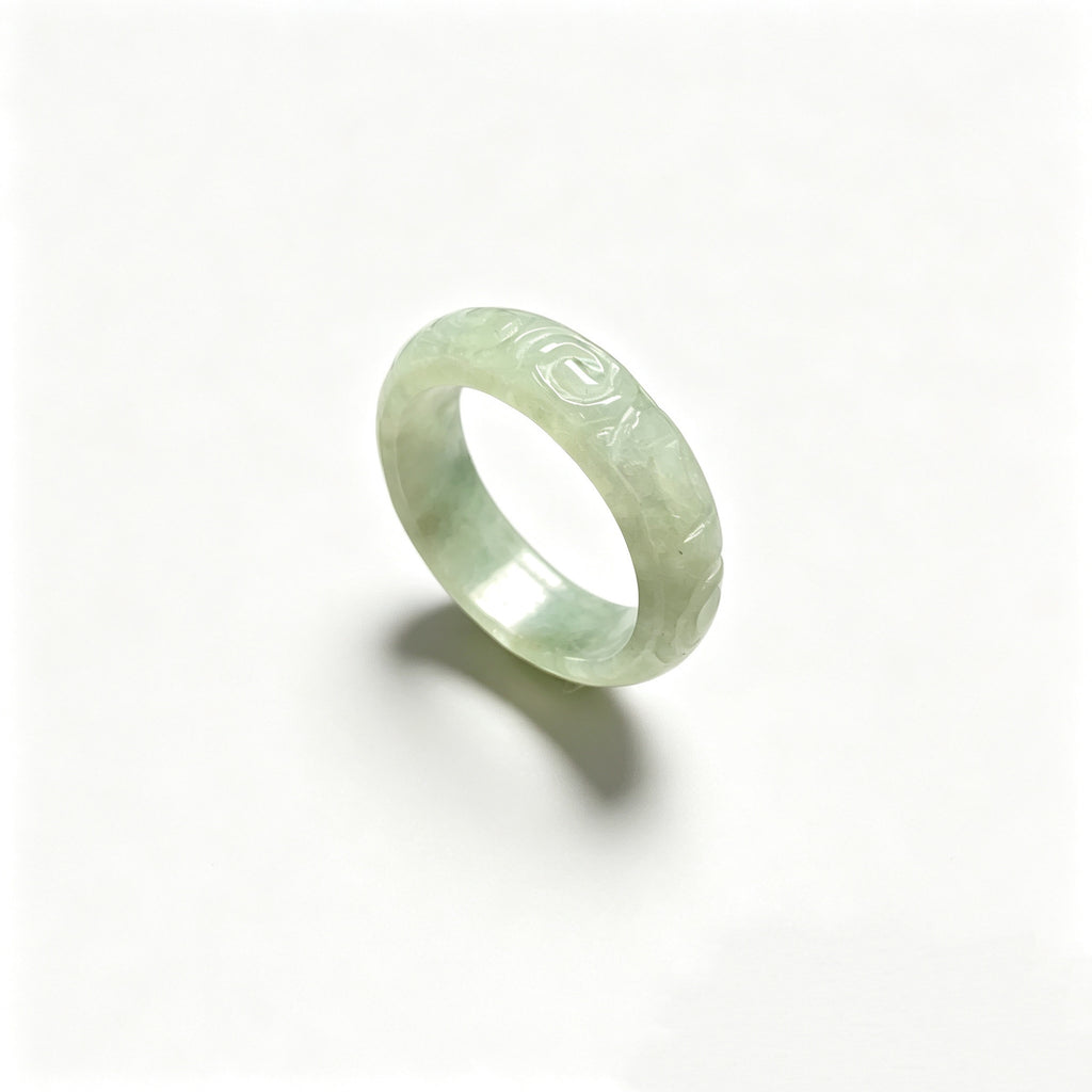 Icy pale green jadeite carved ring on white background with polished interior
