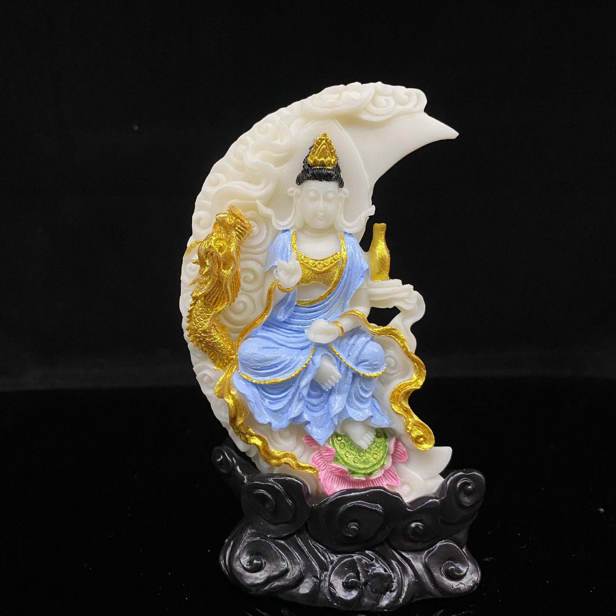 Painted vegetable ivory Guanyin seated within crescent moon with golden dragon and flowing cloud details