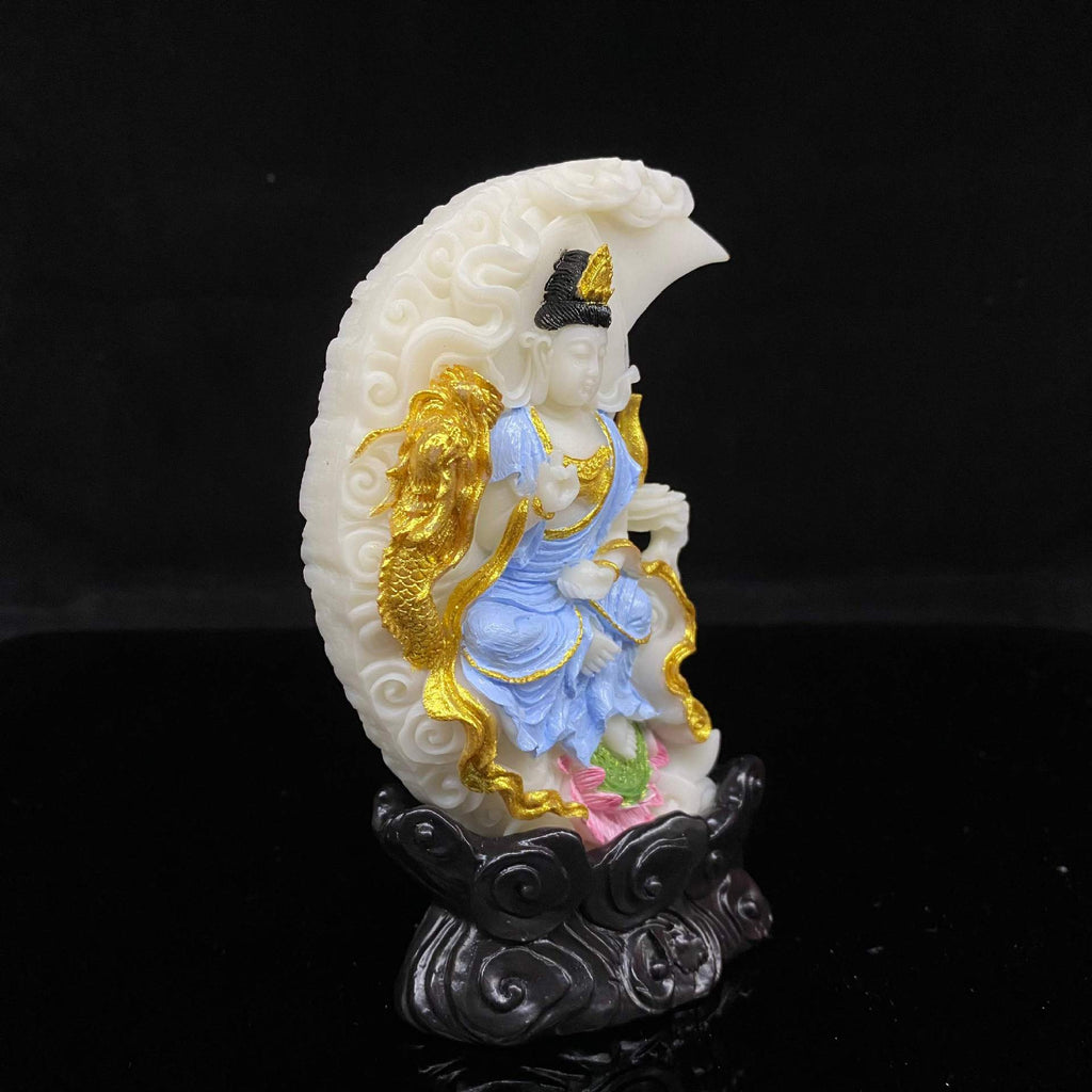 Three-quarter view of painted ivory nut crescent Guanyin statue with golden dragon and cloud base