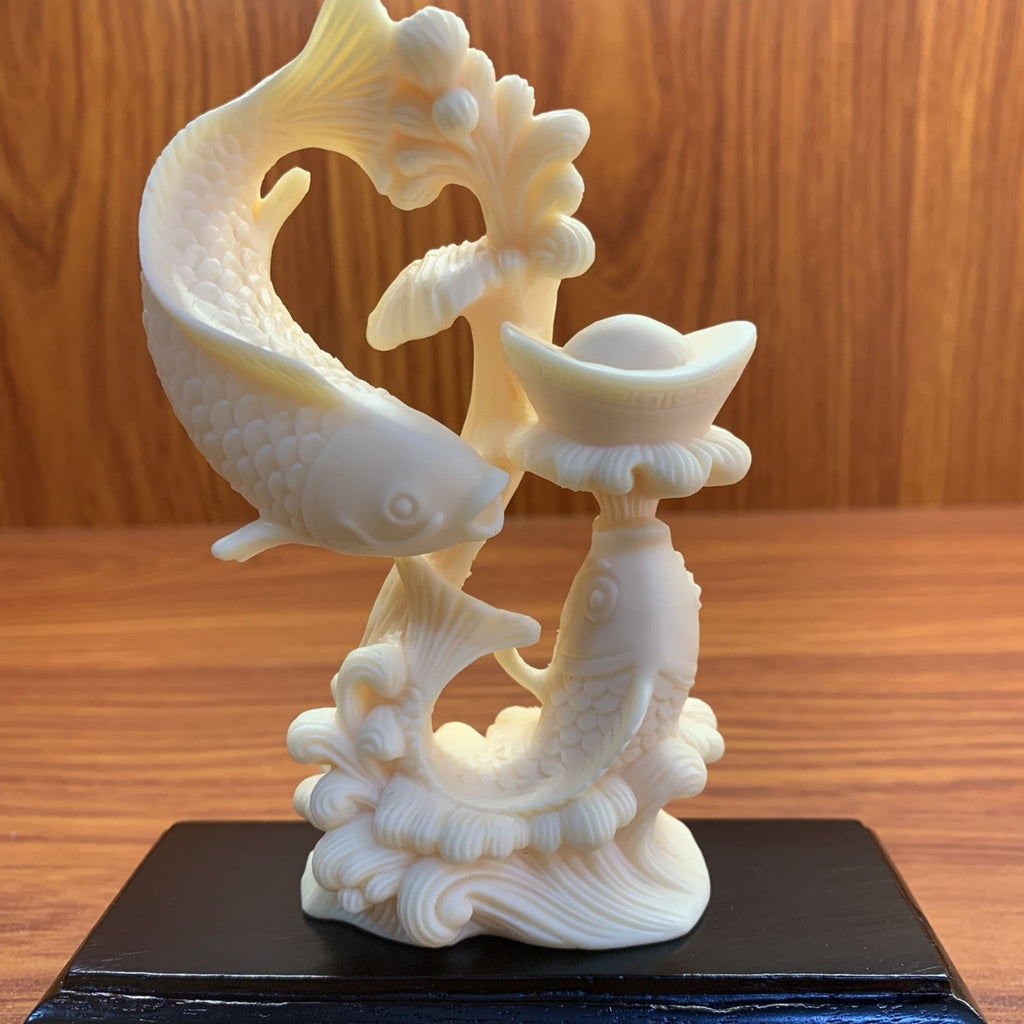 Ivory nut double-fish treasure carving displayed on a dark wooden base