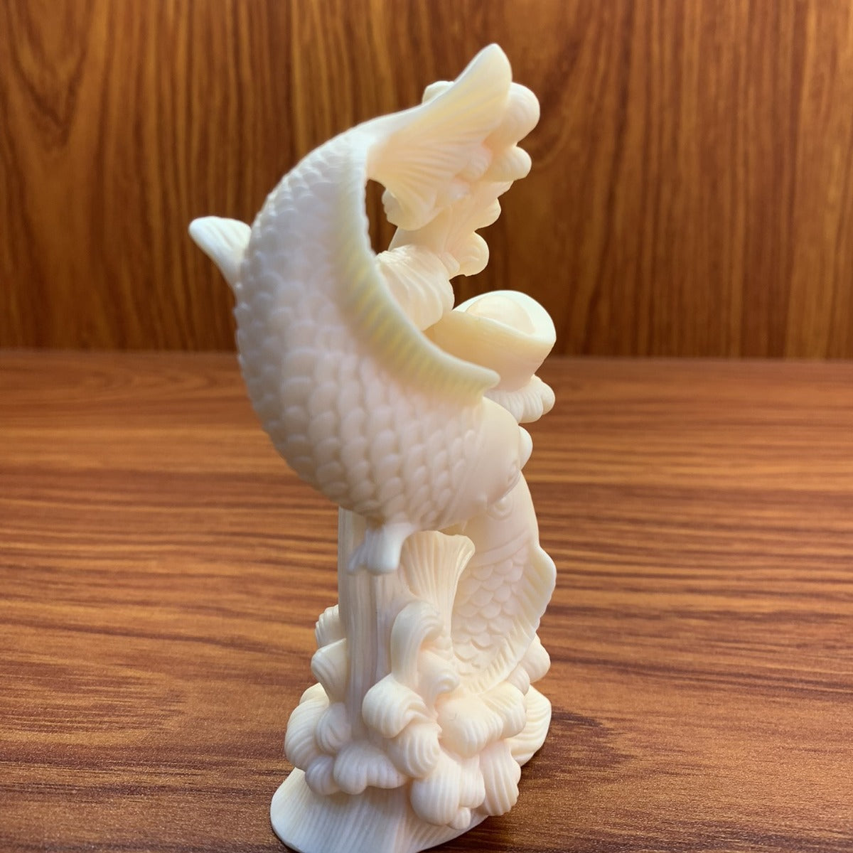 Side view of ivory nut double-fish carving showing layered relief detail