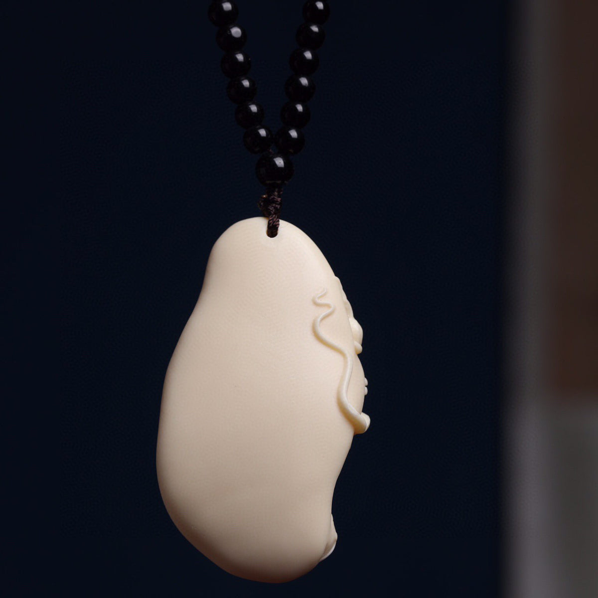 Back view of ivory nut Chinese dragon relief pendant showing smooth natural vegetable ivory surface