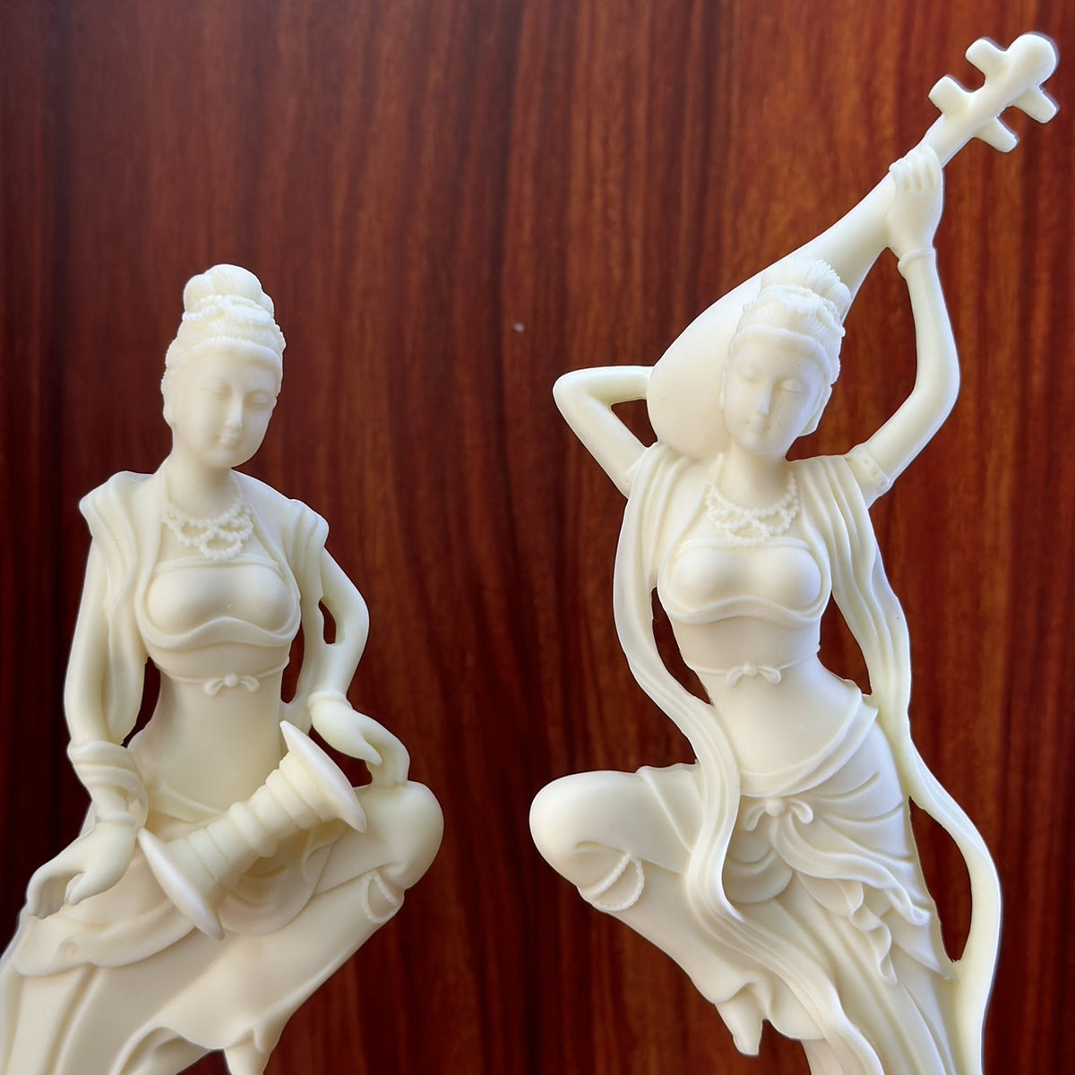 Close detail of natural ivory nut Dunhuang apsara musician pair showing faces, jewelry and instruments
