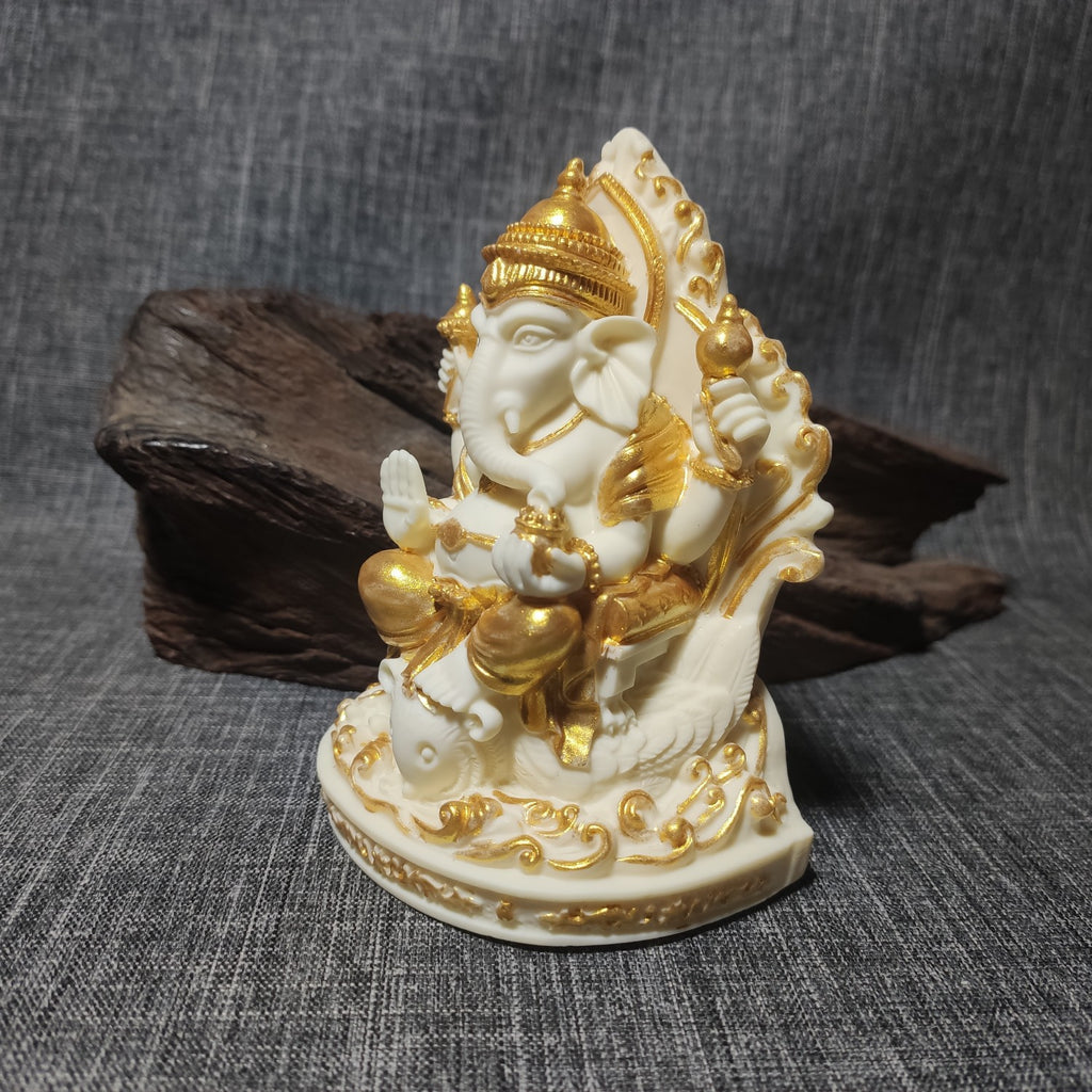 Ivory nut Ganesha decorative statue with gold-tone accents, elephant-headed deity seated on ornate throne