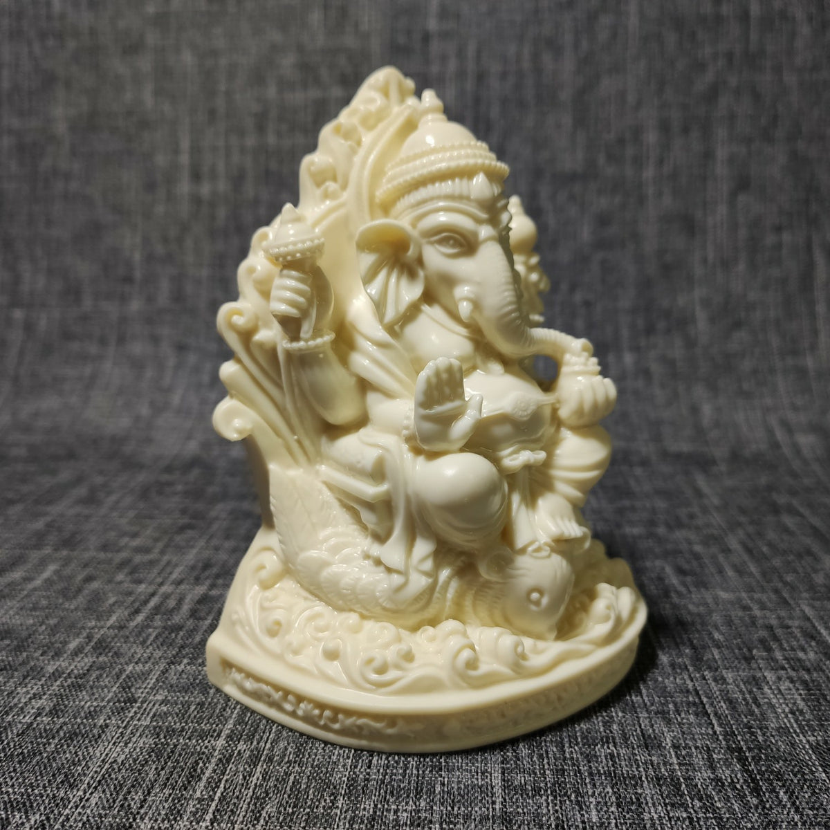 Side view of natural ivory nut Ganesha statue showing throne, crown and sculpted details