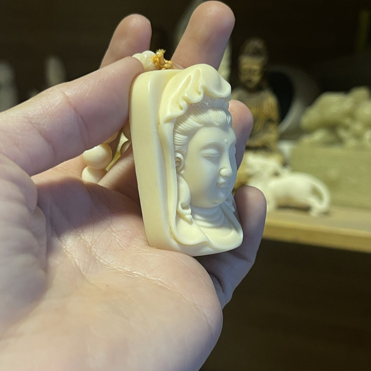 Ivory nut Guanyin carving pendant shown in hand for scale