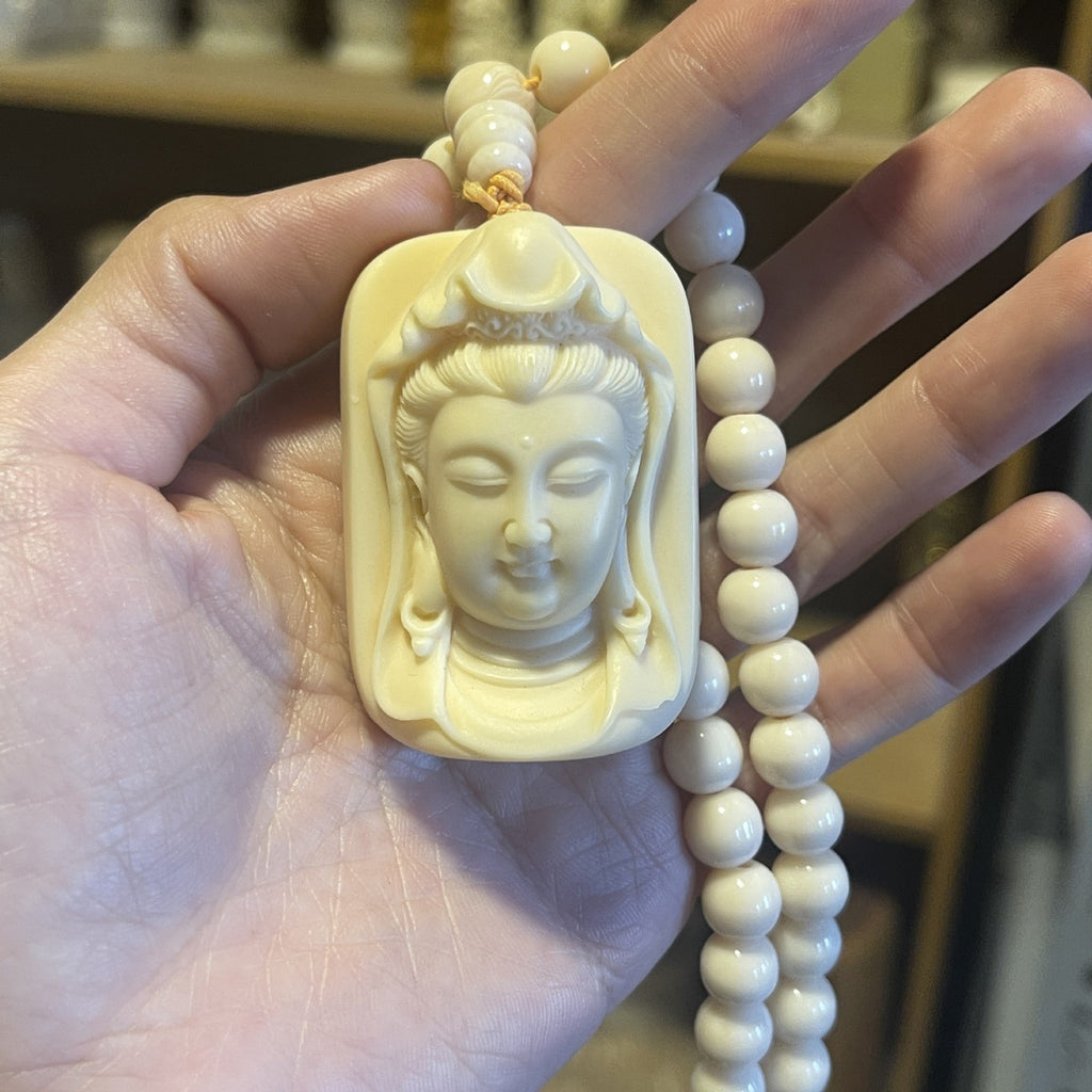 Ivory nut Guanyin pendant with matching bead strand shown in hand
