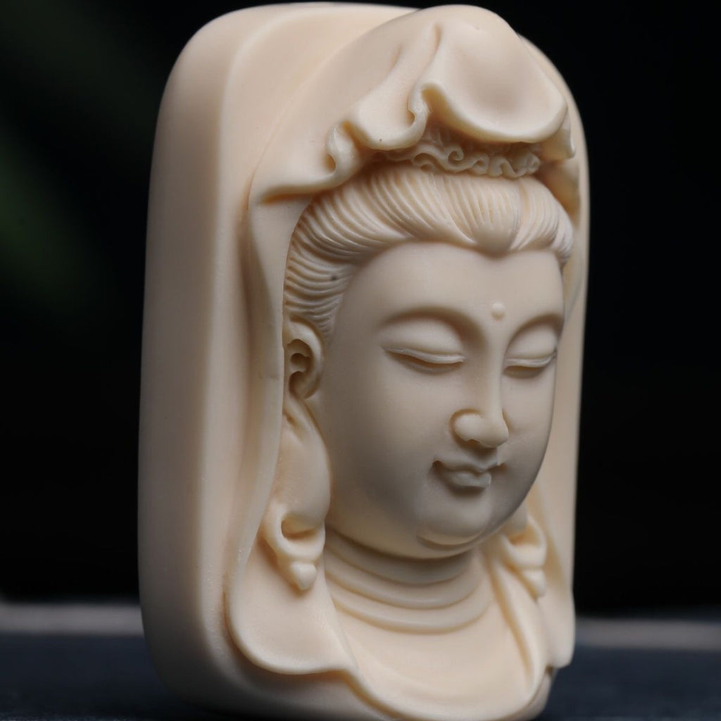 Angled close-up of hand-carved ivory nut Guanyin relief pendant