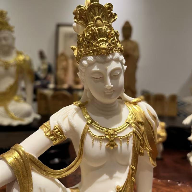 Close-up of ivory nut Guanyin statue with ornate gold-tone crown and robe detailing