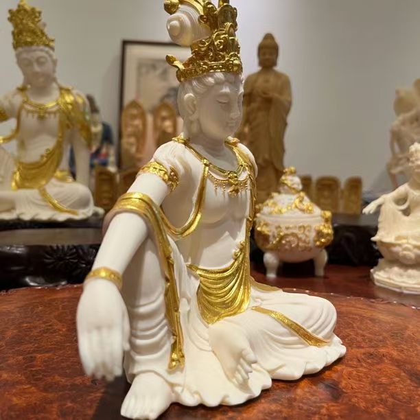 Ivory nut Guanyin decorative statue with gold-tone accents displayed in a collection setting