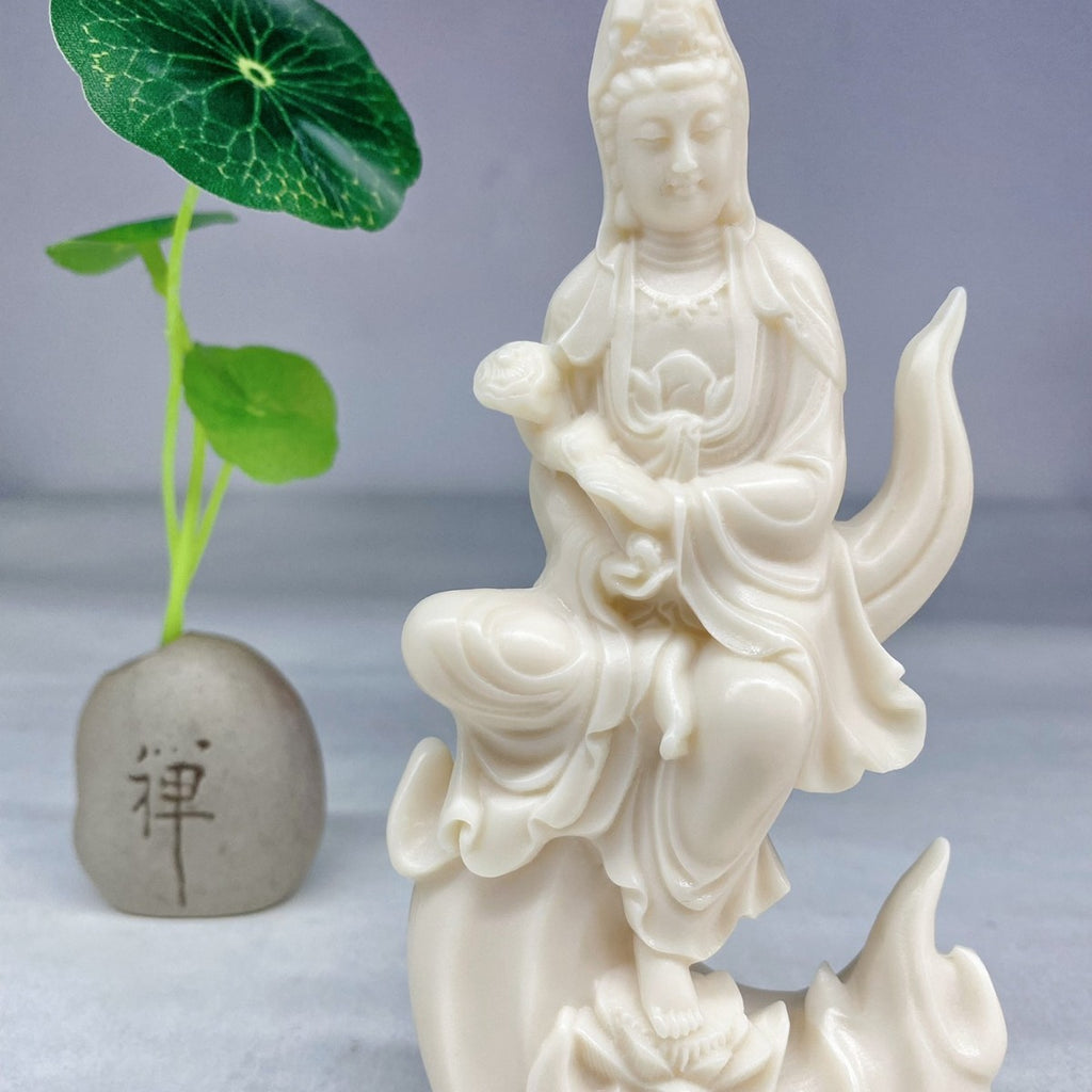 Ivory nut Guanyin figure seated on crescent moon with child and lotus-inspired details