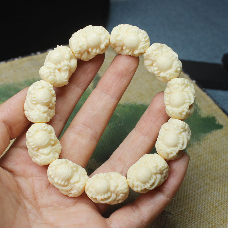 Ivory nut Pixiu carved bead bracelet shown in hand, creamy botanical ivory tone