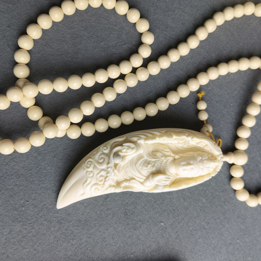 Ivory nut crescent Samantabhadra pendant with carved cloud and flame motifs on bead strand