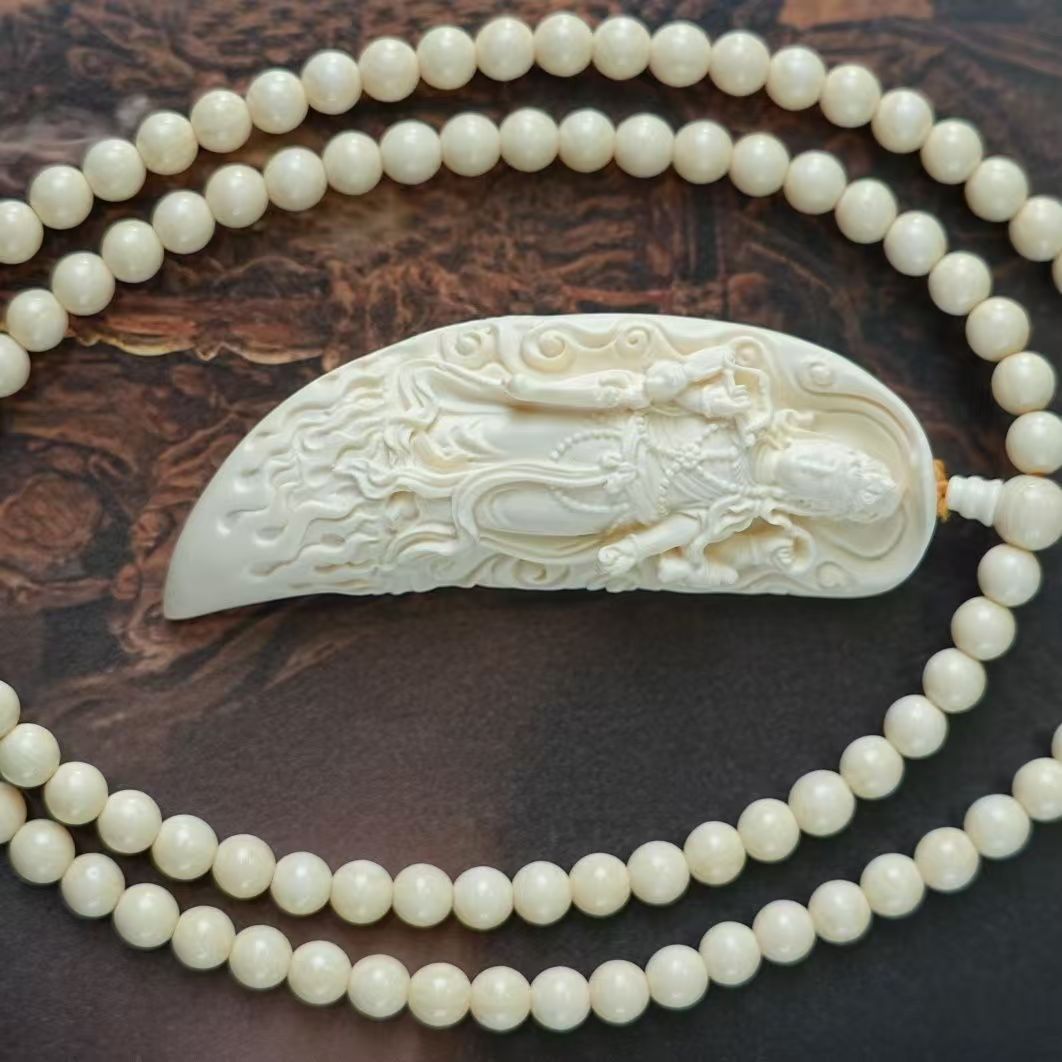 Ivory nut Samantabhadra crescent pendant displayed horizontally with matching pale bead strand