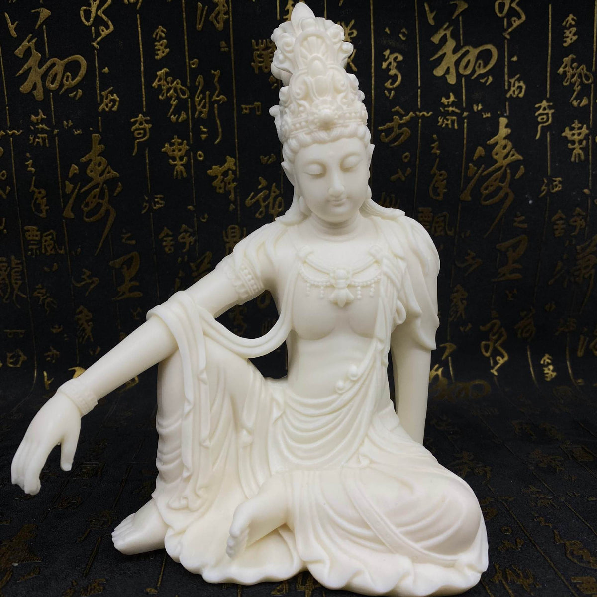 Ivory nut seated Guanyin statue displayed against dark decorative backdrop