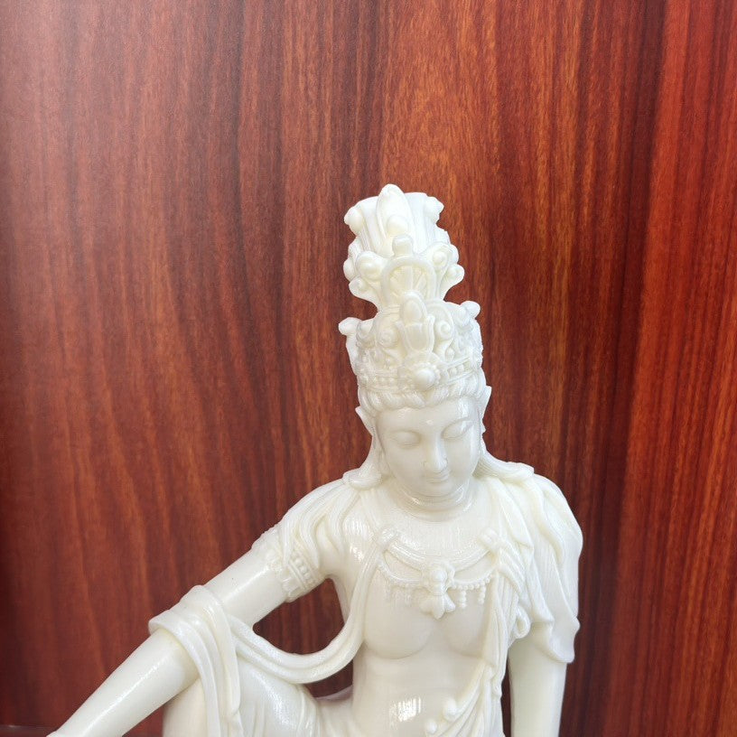 Close-up of ivory nut seated Guanyin face, crown and robe carving details