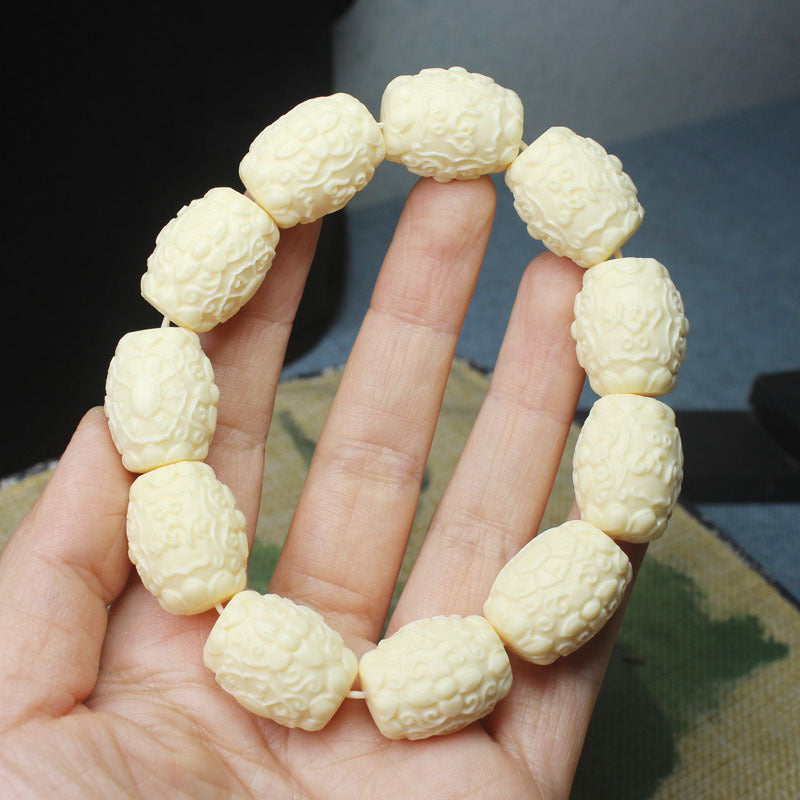 Ivory nut Six-Syllable Mantra relief bead bracelet shown in hand with oval carved beads