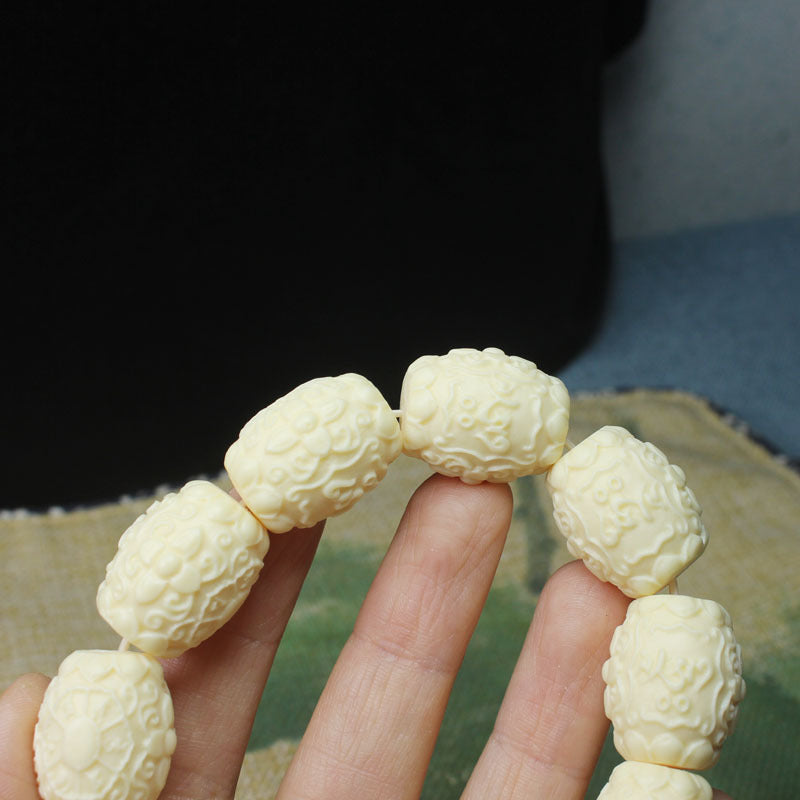Close-up detail of ivory nut Six-Syllable Mantra relief carved beads in creamy botanical ivory tone