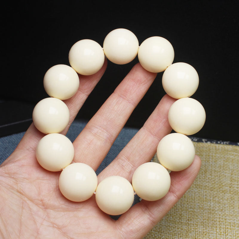 Ivory nut smooth round bead bracelet shown in hand, approximately 20mm creamy botanical ivory beads