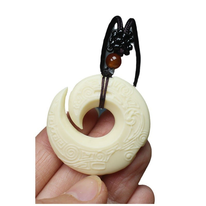 Hand-carved ivory nut spiral fortune pendant with traditional geometric relief and dark cord